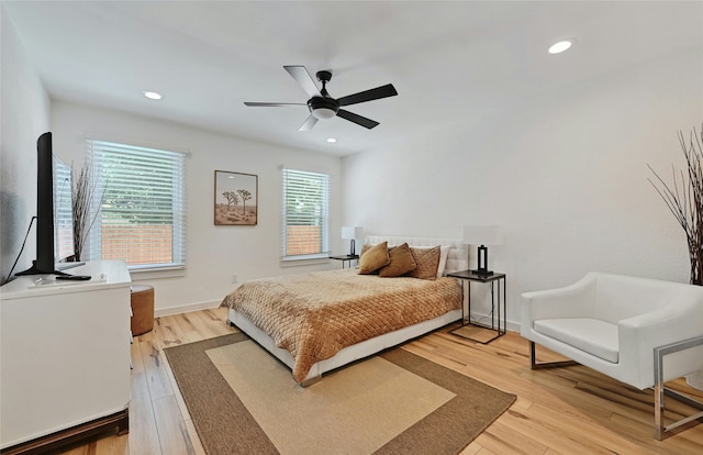 bedroom with ceiling fan, multiple windows, and light hardwood / wood-style flooring