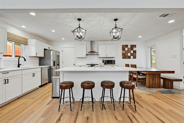 kitchen featuring wall chimney range hood, a center island, and hanging light fixtures