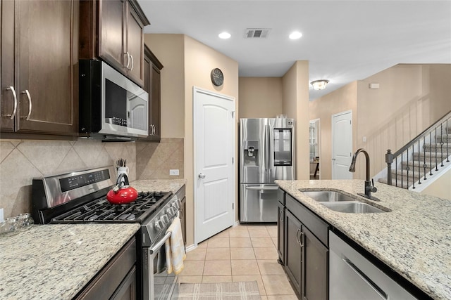 kitchen featuring sink, backsplash, light tile patterned floors, light stone countertops, and stainless steel appliances