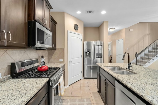 9201 Bentley Garner Ln, Austin, TX 78748 - kitchen with appliances with stainless steel finishes, dark brown cabinetry, light stone counters, decorative backsplash, and light tile patterned floors