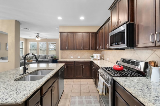 kitchen with sink, tasteful backsplash, light tile patterned floors, light stone counters, and stainless steel appliances