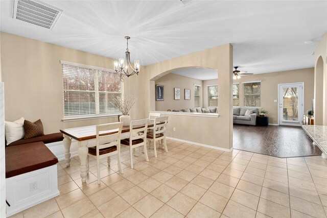 tiled dining space featuring ceiling fan with notable chandelier