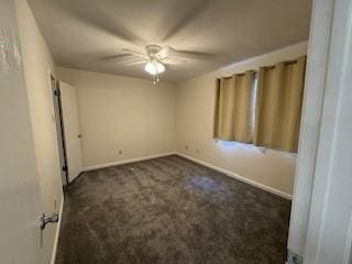 empty room featuring ceiling fan and dark colored carpet