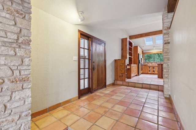 tiled entrance foyer with vaulted ceiling with skylight