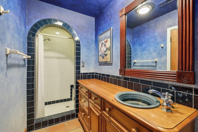 bathroom with tile patterned floors, tile walls, a shower with curtain, vanity, and decorative backsplash