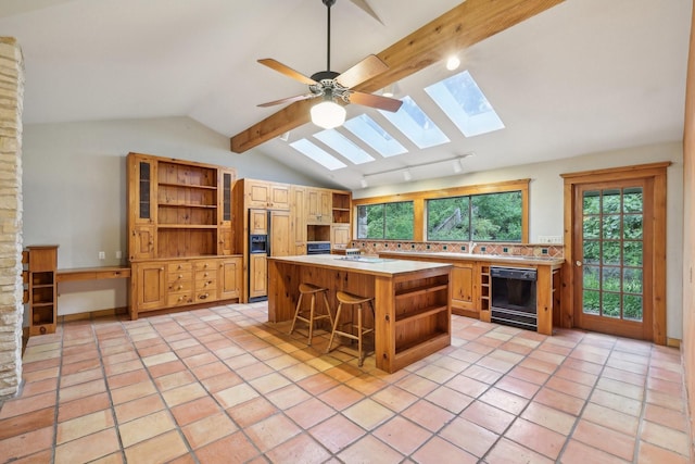 kitchen featuring black dishwasher, a kitchen island, lofted ceiling with beams, a breakfast bar, and light tile patterned flooring