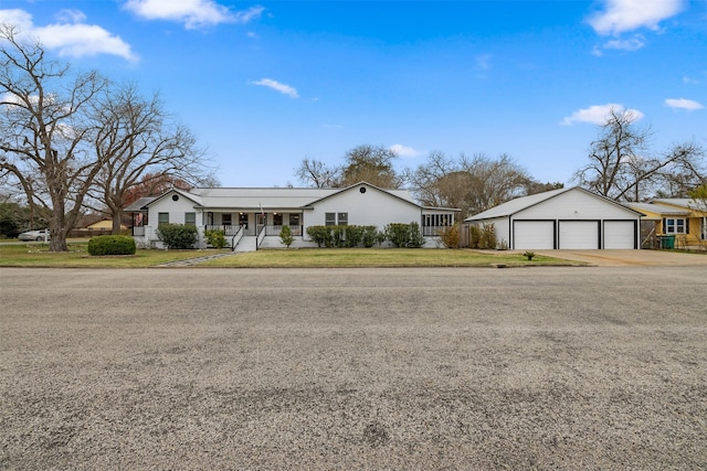 single story home featuring a porch, a garage, and an outbuilding