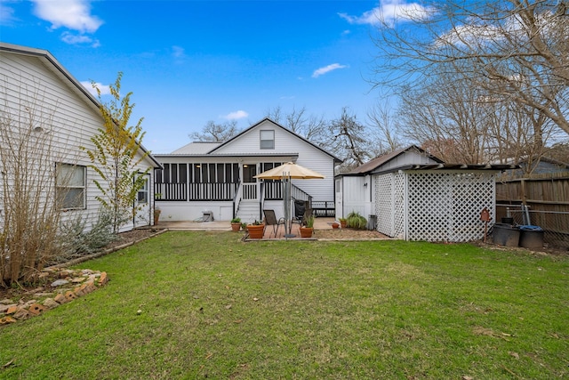 rear view of house with a lawn, a sunroom, and a patio area