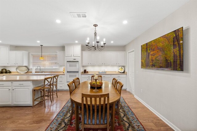 dining area with sink, light hardwood / wood-style flooring, and an inviting chandelier