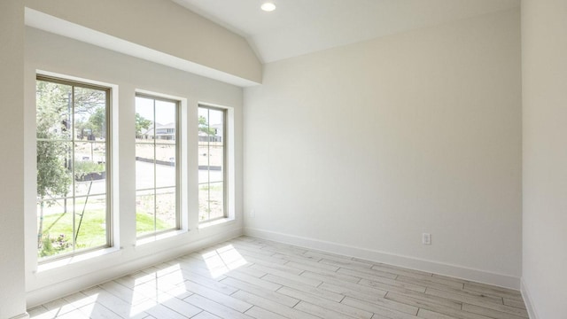 empty room featuring healthy amount of natural light, vaulted ceiling, baseboards, light wood-style floors, and recessed lighting