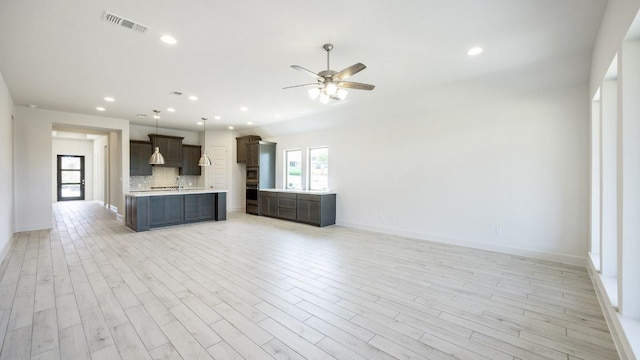 unfurnished living room with ceiling fan, recessed lighting, light wood-style floors, baseboards, and a sink