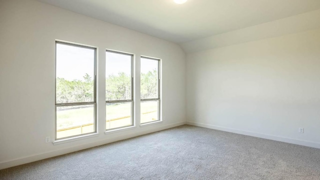 unfurnished room featuring carpet flooring, baseboards, and vaulted ceiling
