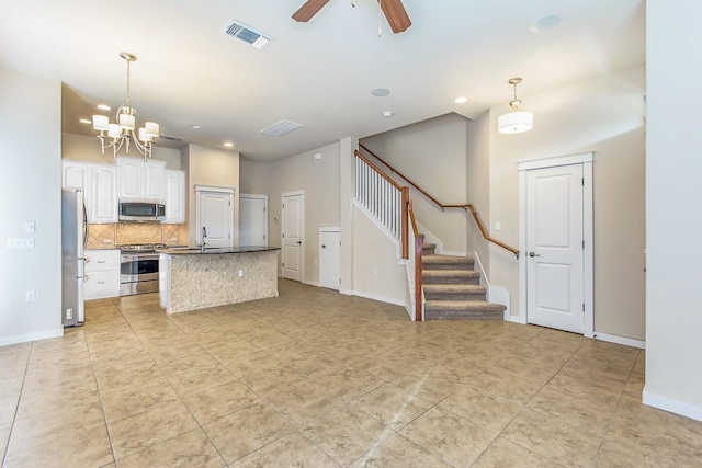 kitchen with white cabinetry, decorative backsplash, decorative light fixtures, stainless steel appliances, and ceiling fan with notable chandelier