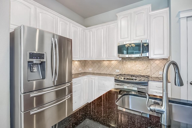 kitchen with sink, white cabinets, dark stone counters, decorative backsplash, and stainless steel appliances