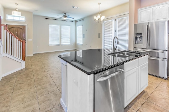 kitchen with white cabinets, decorative light fixtures, stainless steel appliances, light tile patterned floors, and a center island with sink