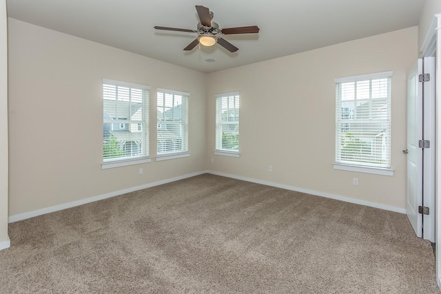 spare room featuring ceiling fan, light colored carpet, and a healthy amount of sunlight