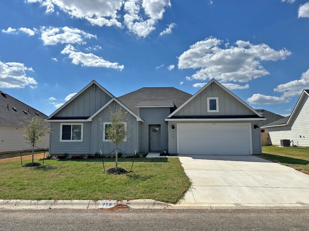 view of front of home featuring a garage, central AC unit, and a front yard