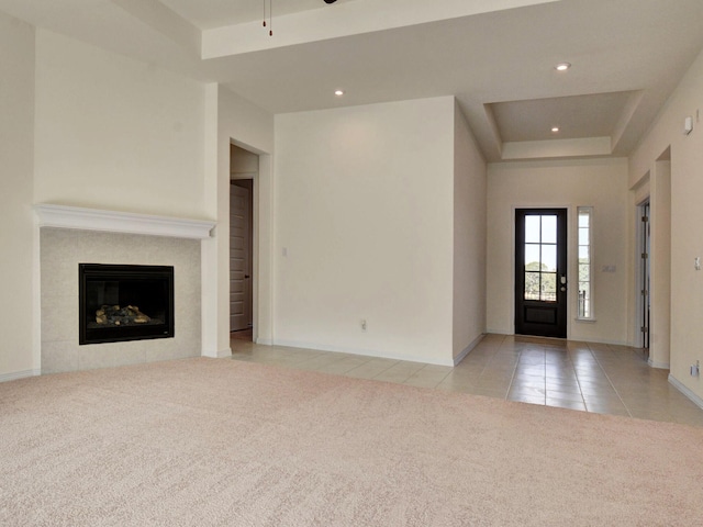 foyer entrance featuring ceiling fan, a tiled fireplace, light tile patterned floors, and a tray ceiling