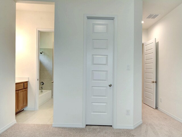 unfurnished bedroom featuring light carpet and connected bathroom