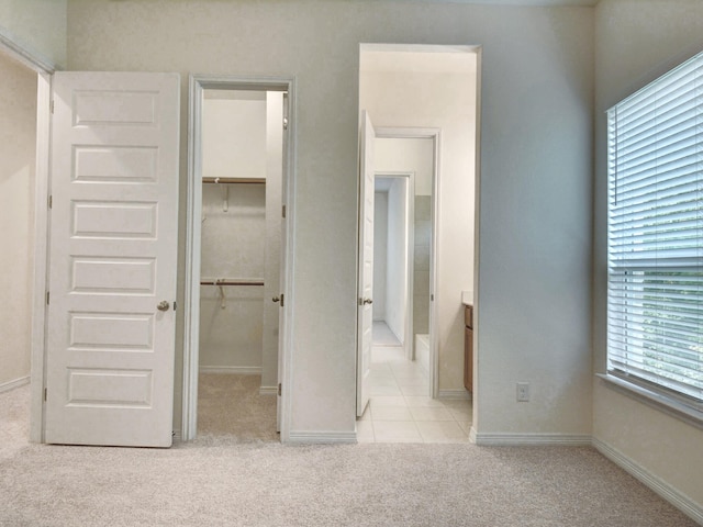 unfurnished bedroom featuring a spacious closet, a closet, and light carpet