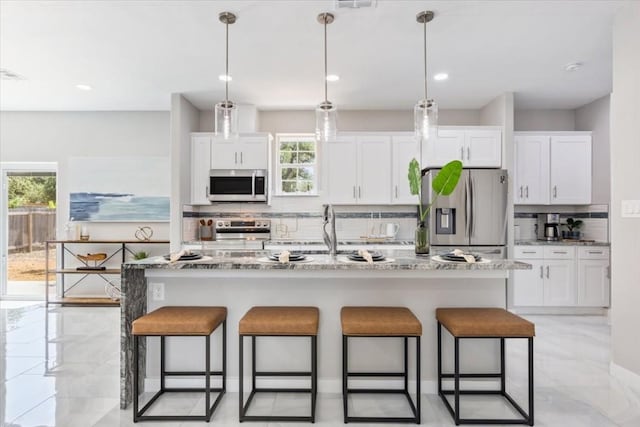 kitchen featuring a healthy amount of sunlight, appliances with stainless steel finishes, a kitchen breakfast bar, and decorative backsplash