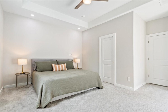 carpeted bedroom featuring ceiling fan and a raised ceiling