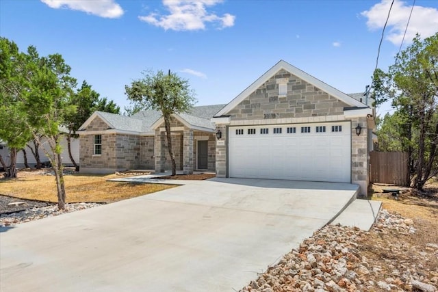 ranch-style home featuring driveway, fence, stone siding, and a garage
