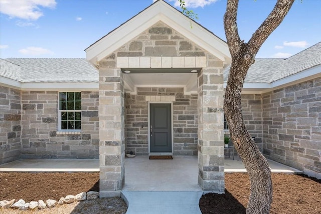 property entrance with stone siding and a shingled roof
