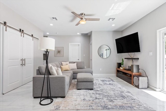 living room featuring ceiling fan and a barn door