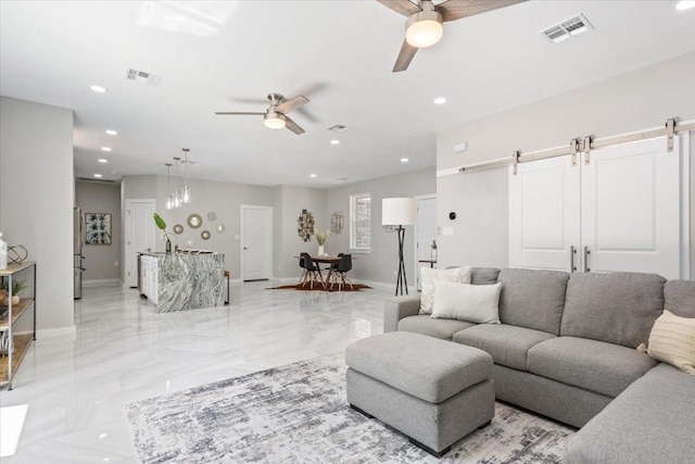 living room with ceiling fan and a barn door