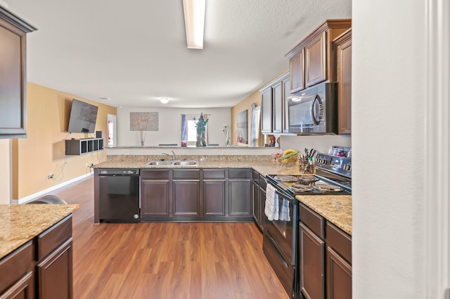 kitchen featuring black appliances, light hardwood / wood-style floors, sink, dark brown cabinetry, and kitchen peninsula