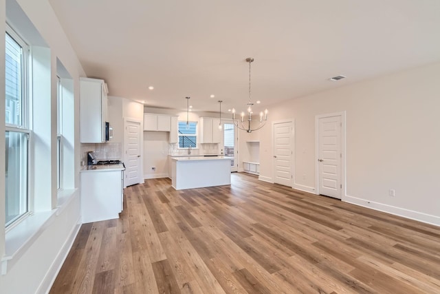 kitchen featuring a kitchen island, white cabinets, decorative light fixtures, and tasteful backsplash