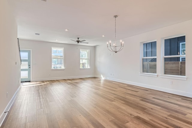 unfurnished room with ceiling fan with notable chandelier and light hardwood / wood-style flooring