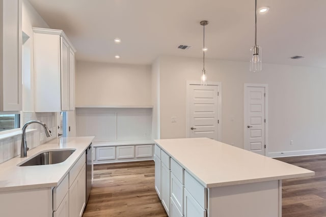 kitchen with pendant lighting, dishwasher, a center island, white cabinetry, and sink