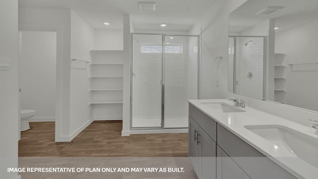 bathroom featuring hardwood / wood-style flooring, toilet, a shower with shower door, and vanity