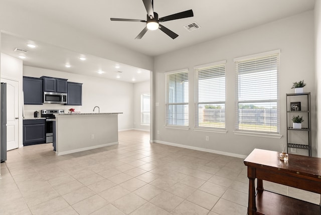 tiled living room featuring ceiling fan, sink, and a wealth of natural light