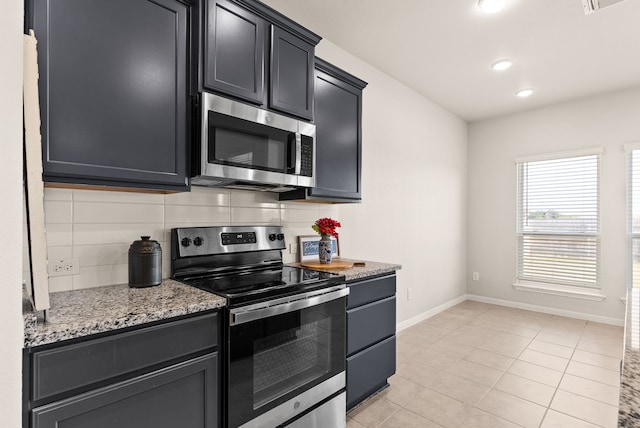 kitchen featuring light stone counters, light tile patterned floors, appliances with stainless steel finishes, and decorative backsplash