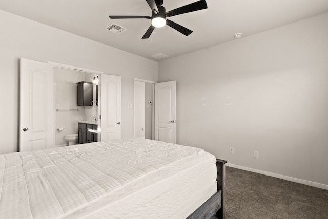 bedroom with ceiling fan, dark carpet, and ensuite bath