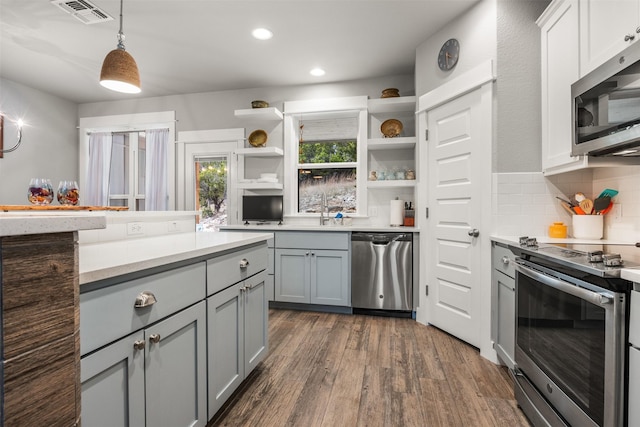 kitchen with appliances with stainless steel finishes, decorative light fixtures, tasteful backsplash, gray cabinets, and dark hardwood / wood-style floors