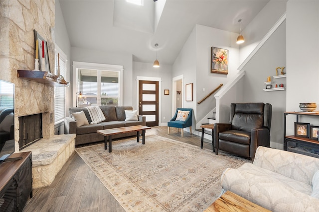 living room featuring wood-type flooring, high vaulted ceiling, and a fireplace