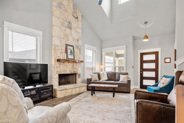 living room with wood-type flooring, a high ceiling, and a stone fireplace