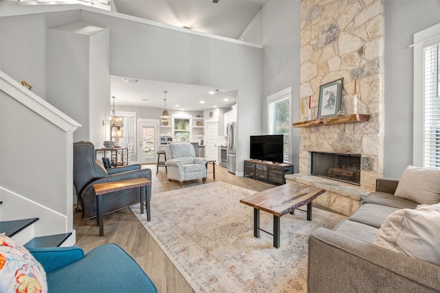 living room featuring high vaulted ceiling, light hardwood / wood-style flooring, a healthy amount of sunlight, and a fireplace