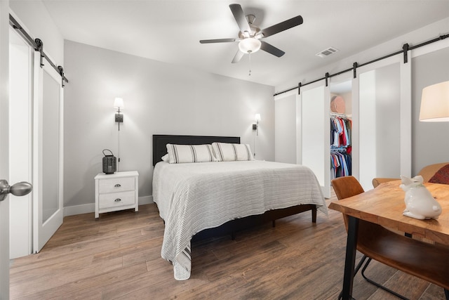 bedroom with hardwood / wood-style flooring, a closet, ceiling fan, and a barn door