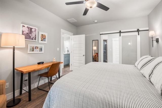 bedroom with ceiling fan, ensuite bathroom, a barn door, and dark hardwood / wood-style floors