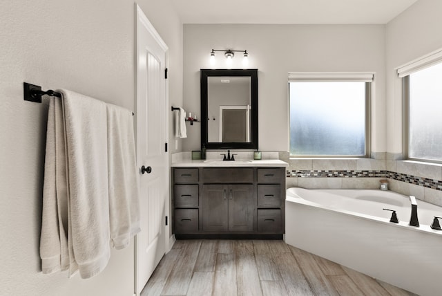 bathroom featuring vanity, hardwood / wood-style flooring, a wealth of natural light, and a washtub