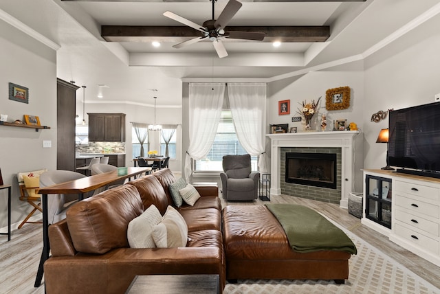 living room featuring a fireplace, light wood-type flooring, beamed ceiling, and ceiling fan