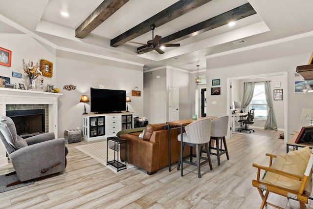 living room featuring a fireplace, light hardwood / wood-style floors, a tray ceiling, and ornamental molding