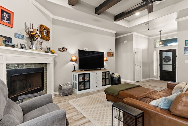 living room featuring a high end fireplace, crown molding, light wood-type flooring, beam ceiling, and ceiling fan