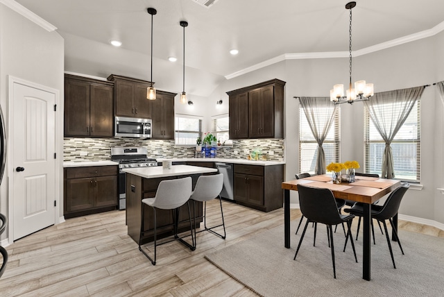 kitchen with light wood-type flooring, decorative light fixtures, a center island, and appliances with stainless steel finishes