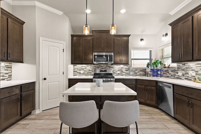 kitchen with hanging light fixtures, decorative backsplash, sink, a kitchen island, and stainless steel appliances